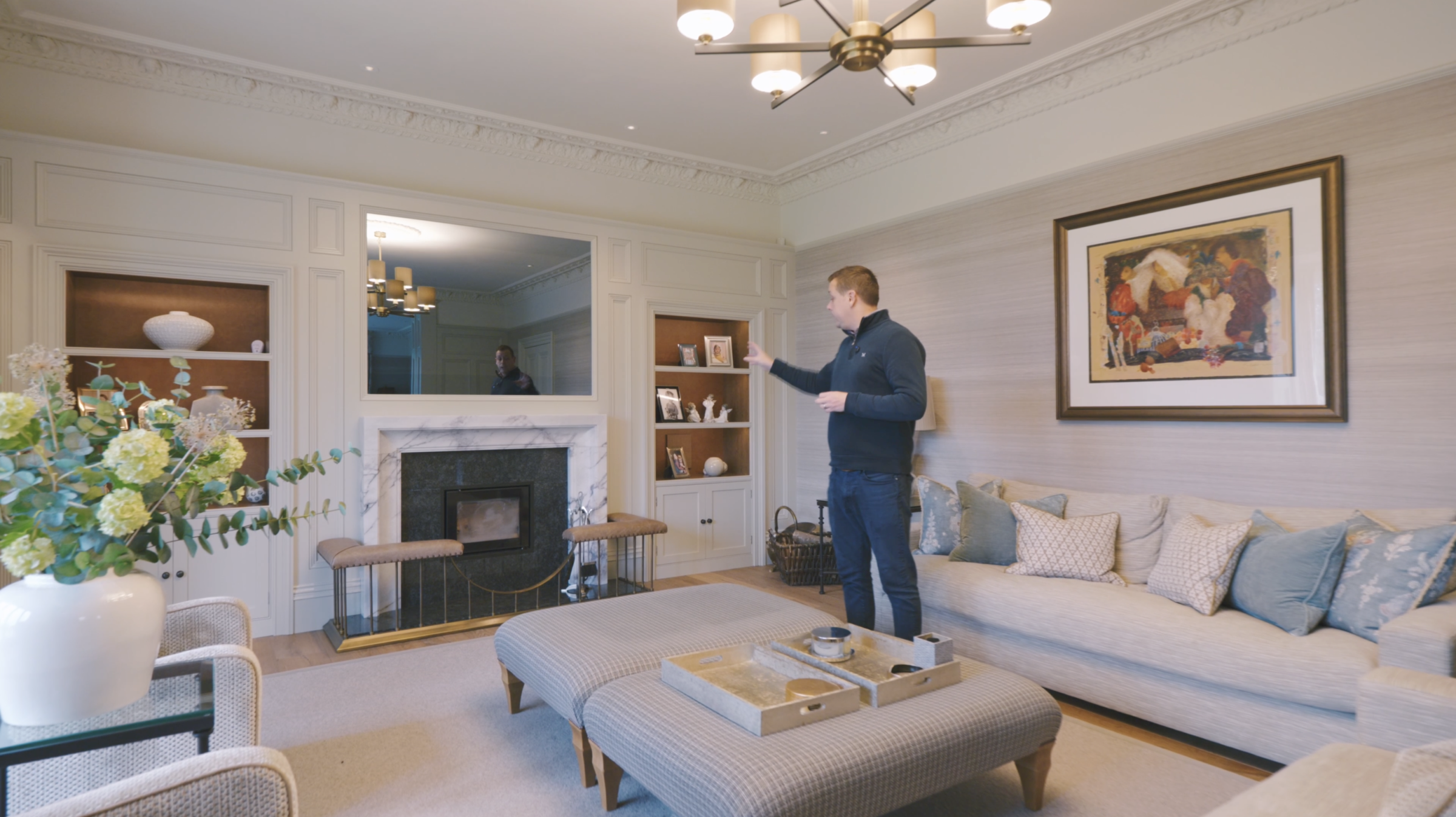 Simon in the lounge with a large fireplace and TV above