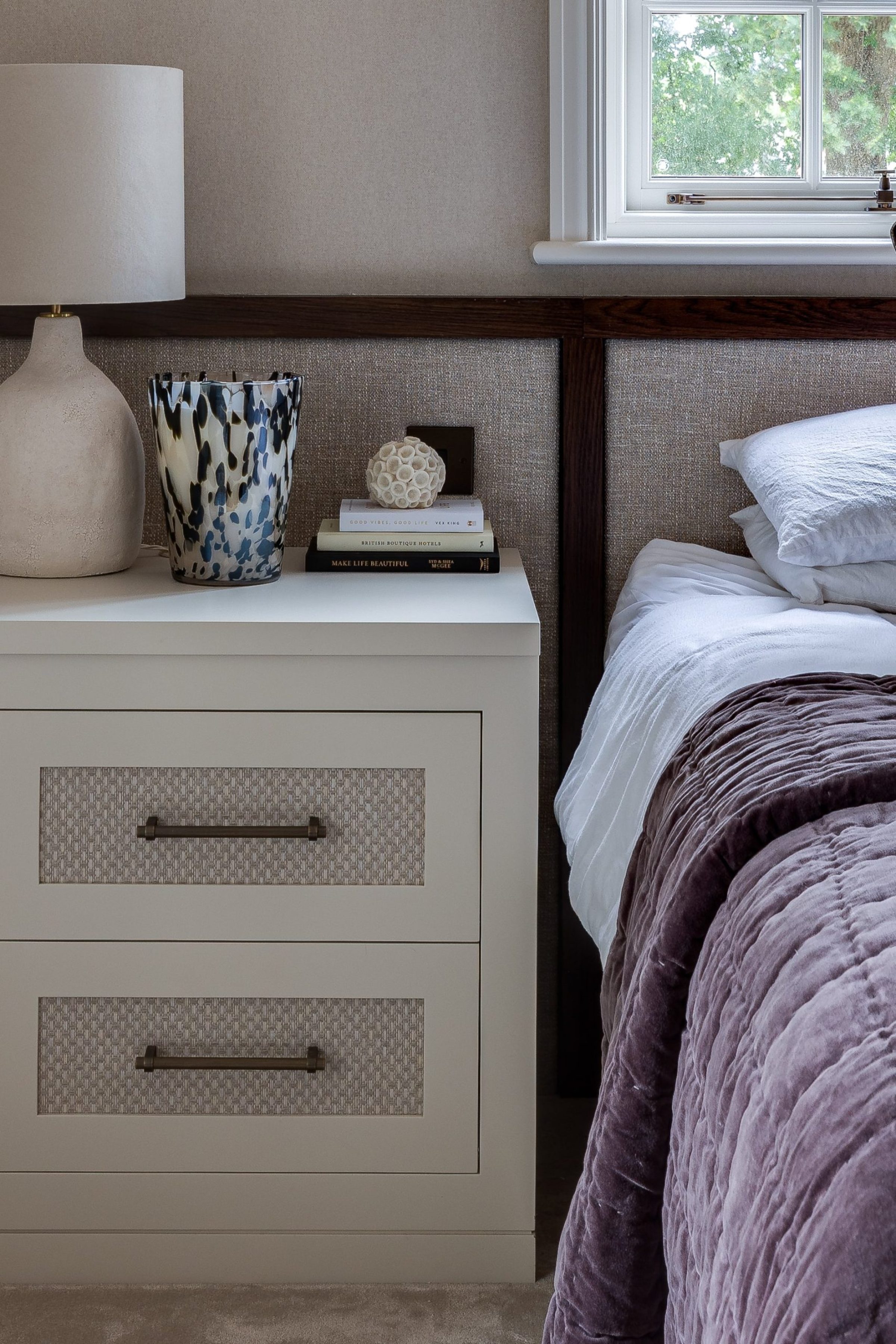 Bedroom with upholstered headboard, built-in bedside drawers and soft layered styling