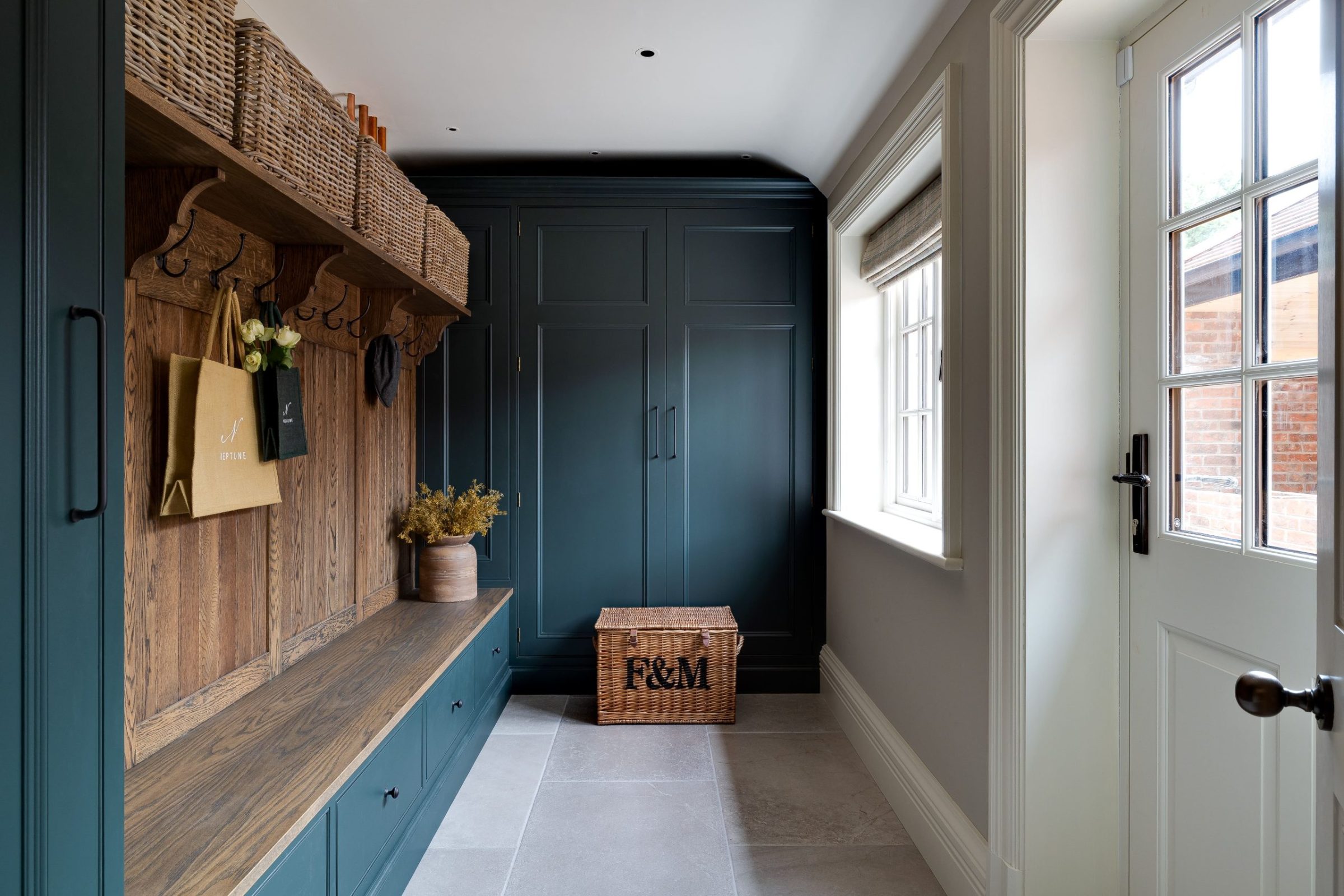 Boot room with painted cabinetry, oak bench and integrated basket storage