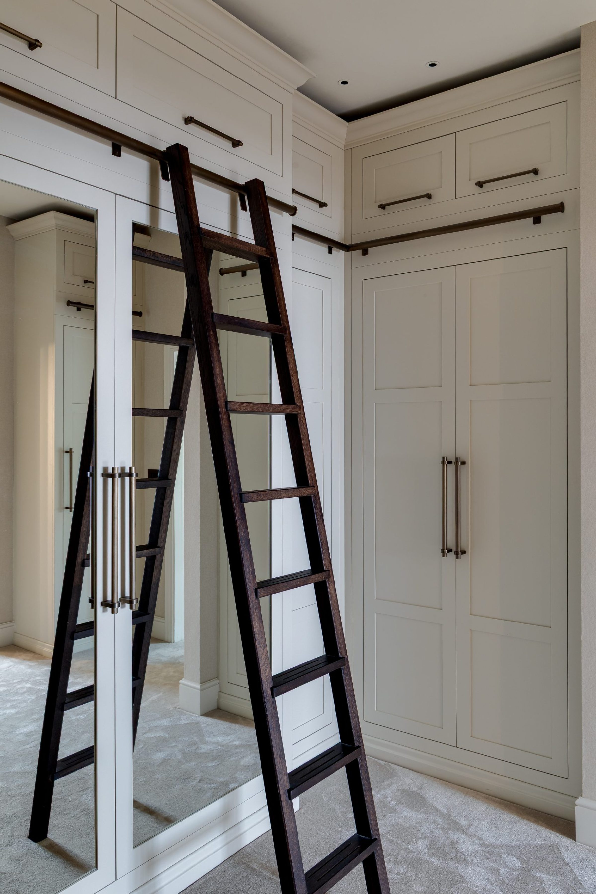 Dressing room with full-height cabinetry, integrated ladder and soft neutral palette