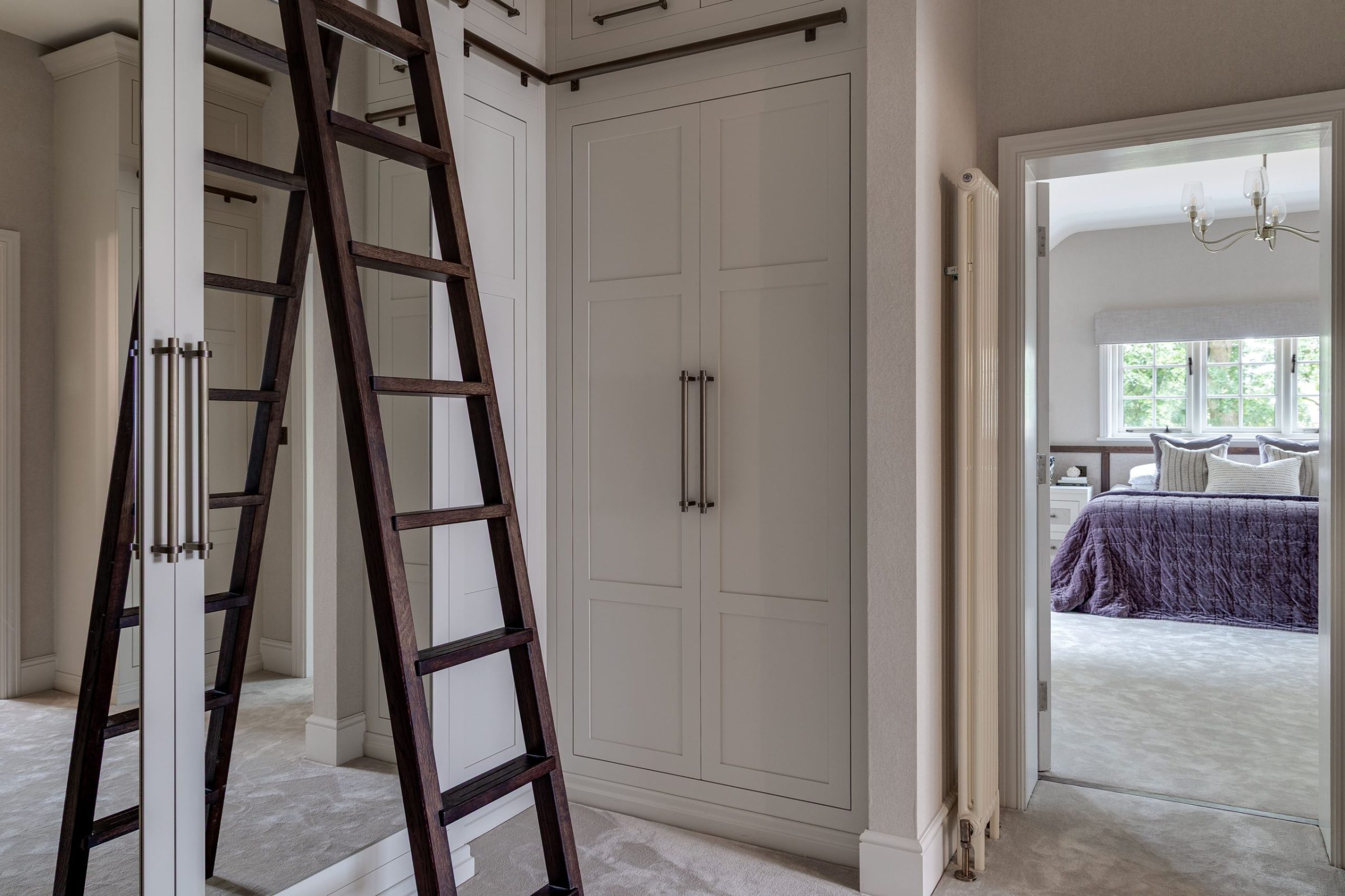 Dressing room with full-height cabinetry, integrated ladder and soft neutral palette