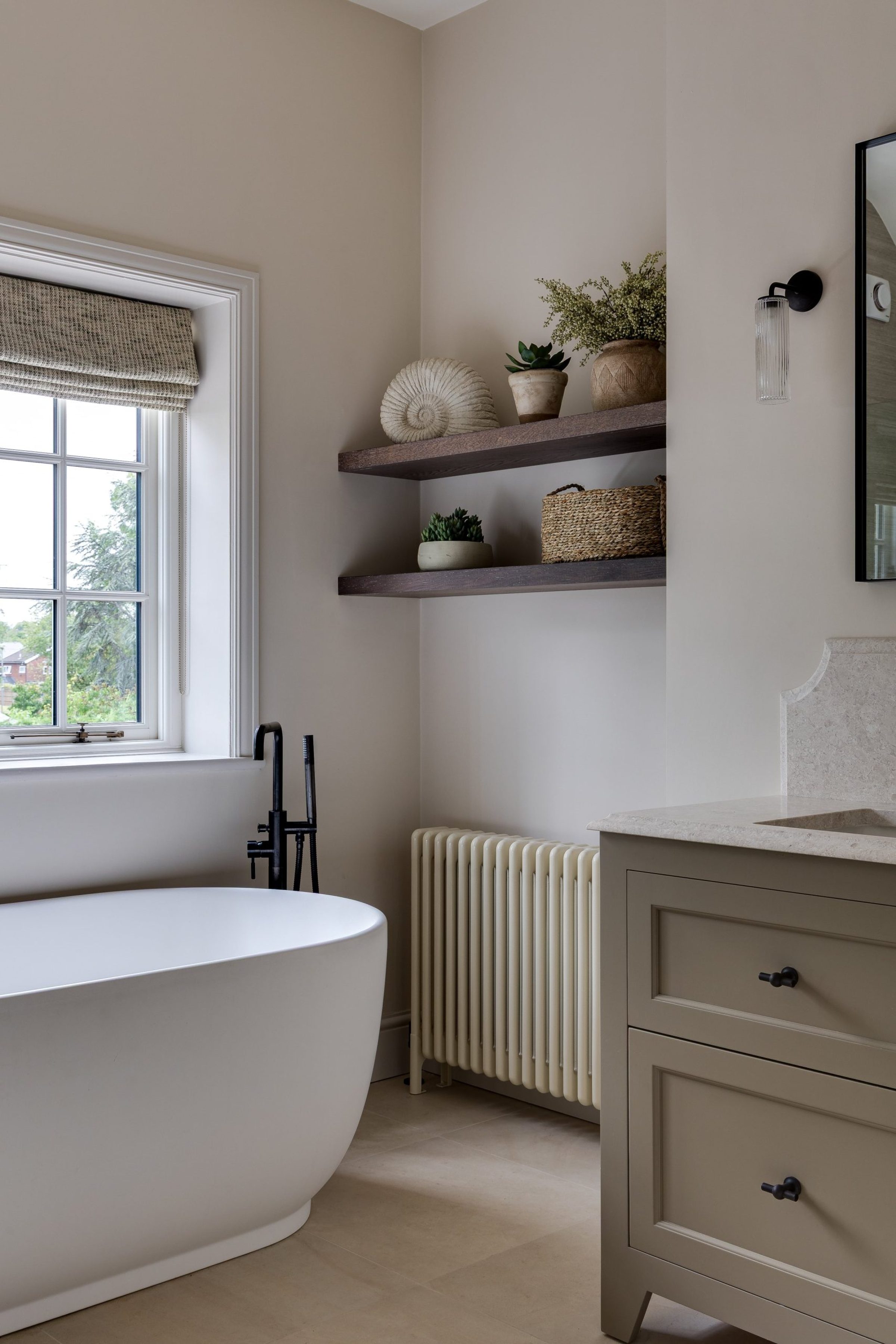 Freestanding bath with matte black tapware and natural wood shelving