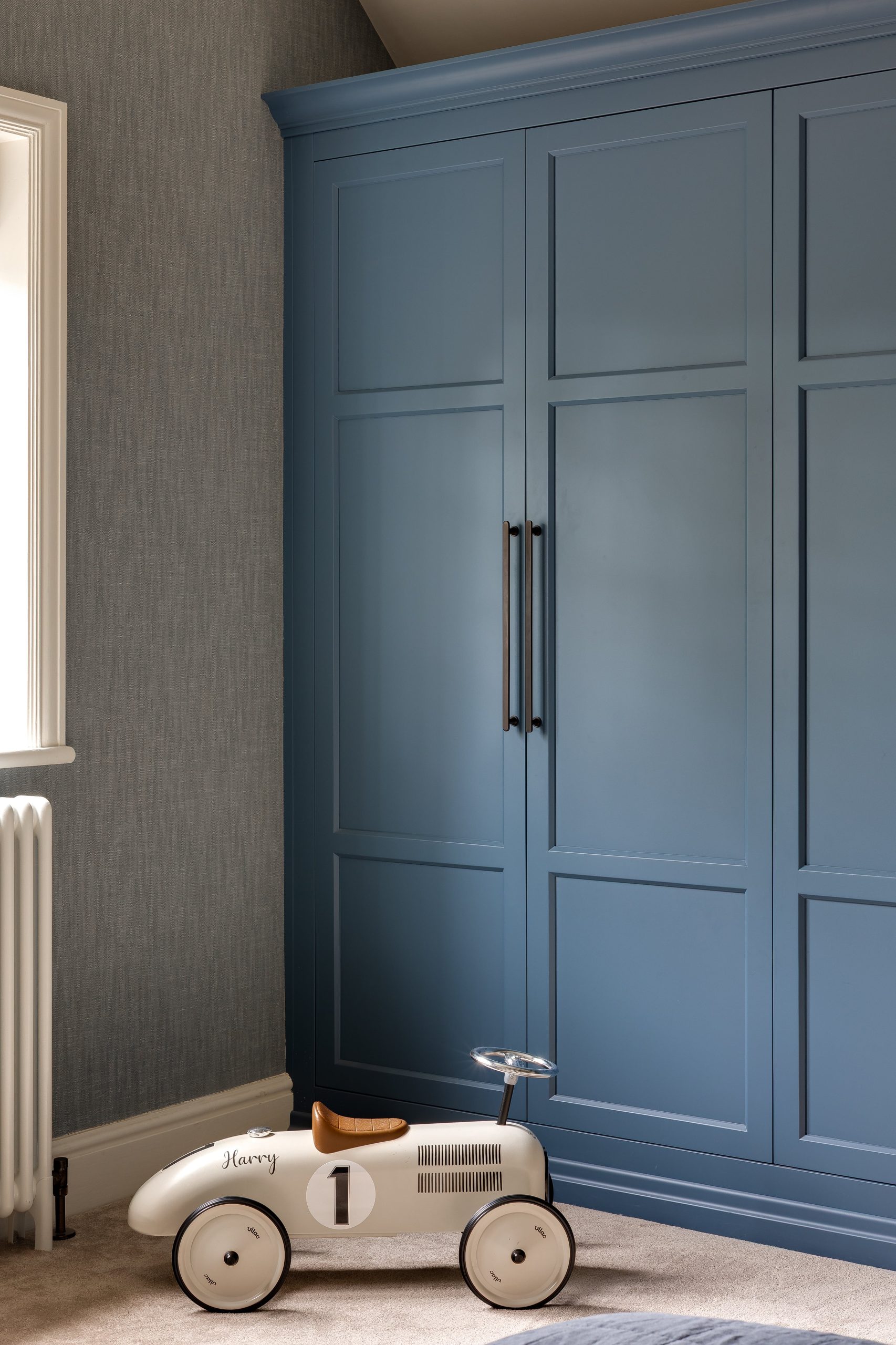 Children’s wardrobe with blue-painted joinery and brushed bronze handles