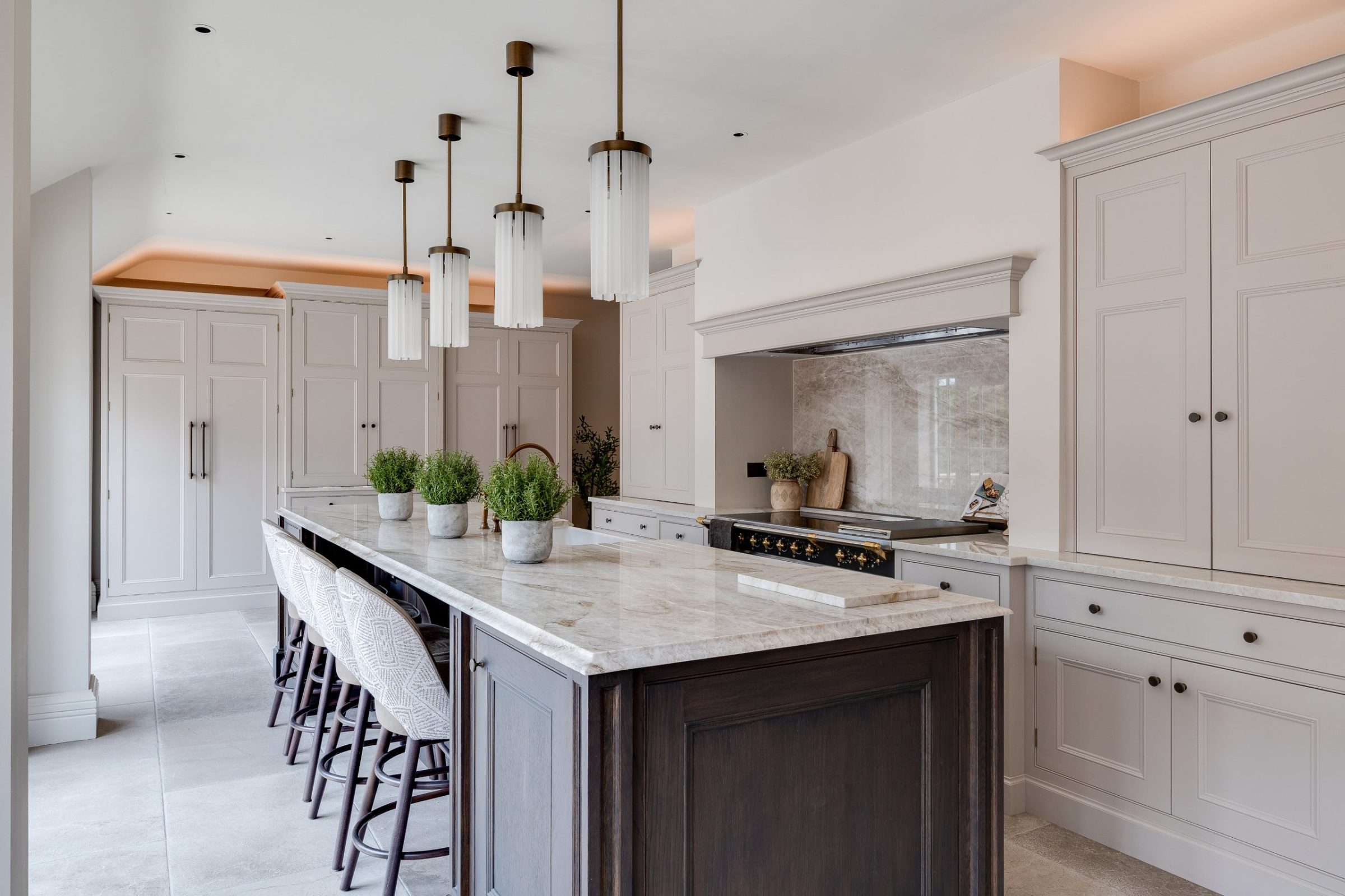 Large kitchen island with stone worktop, dark base units and pendant lights