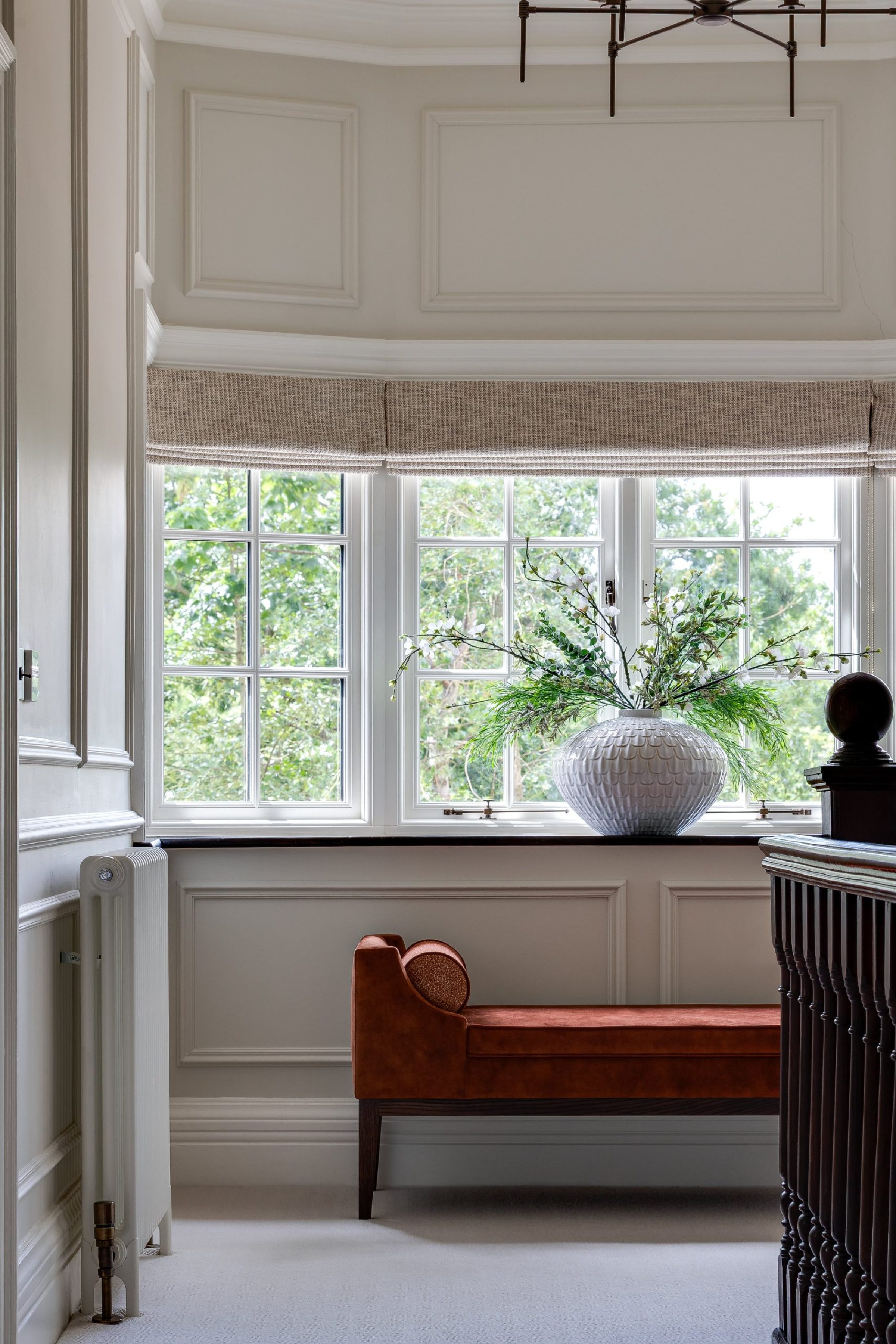 Landing window with textured roman blind, fluted vase and burnt orange bench seat