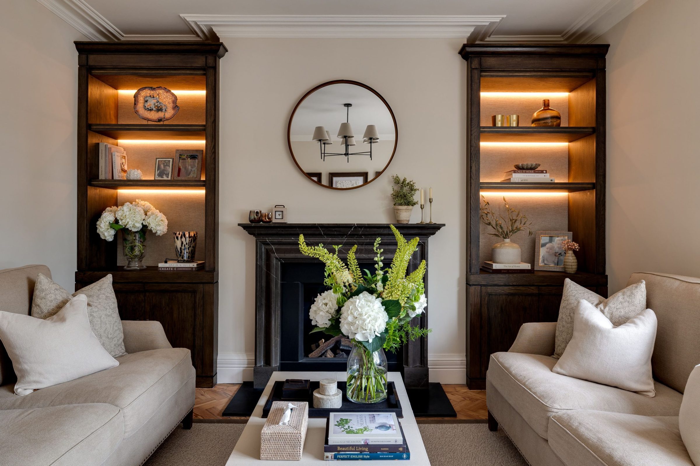 Lounge with twin alcove shelving, round mirror and dark fireplace surround