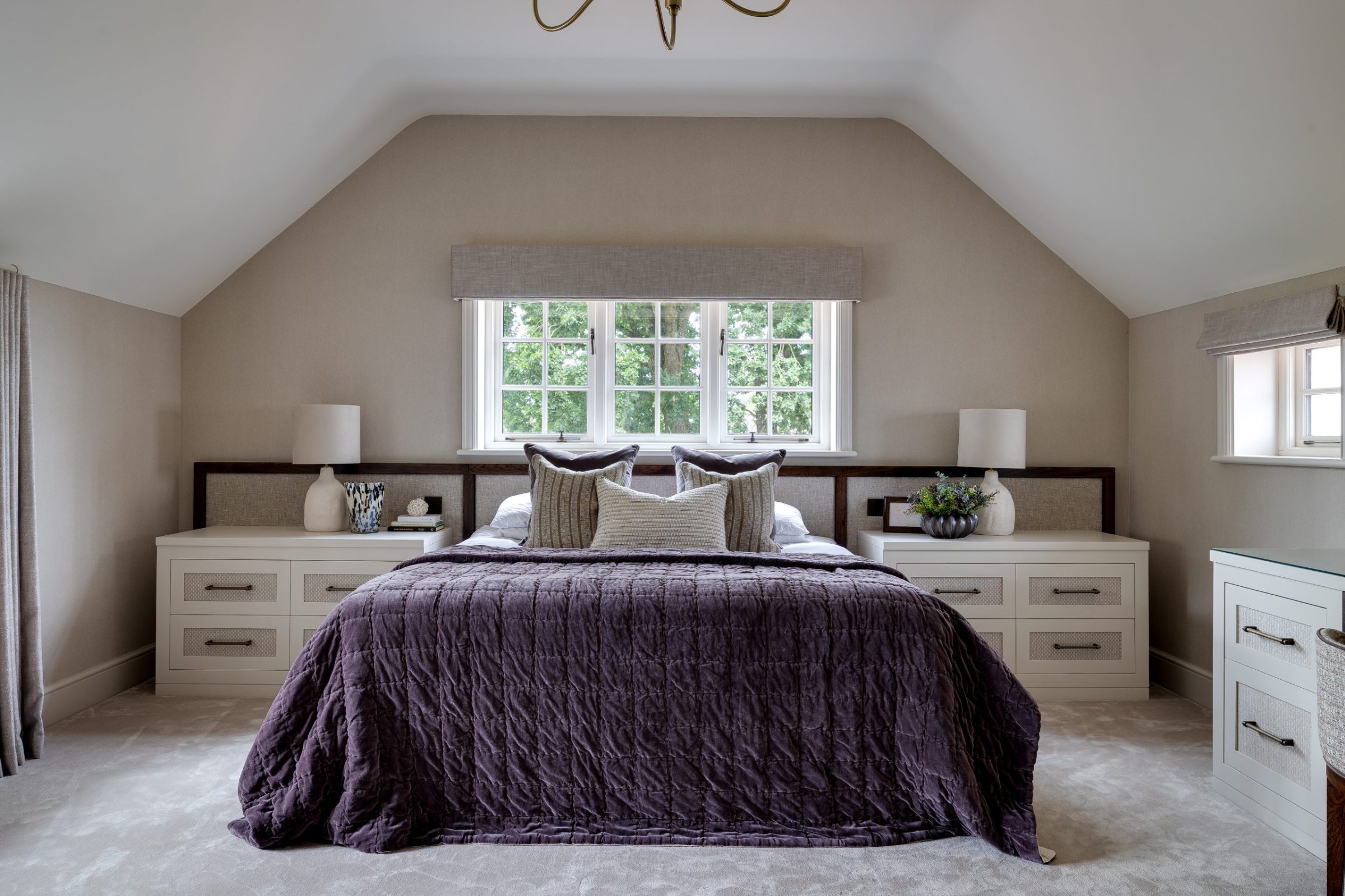Master bedroom with sloped ceiling, upholstered headboard and layered bedside styling