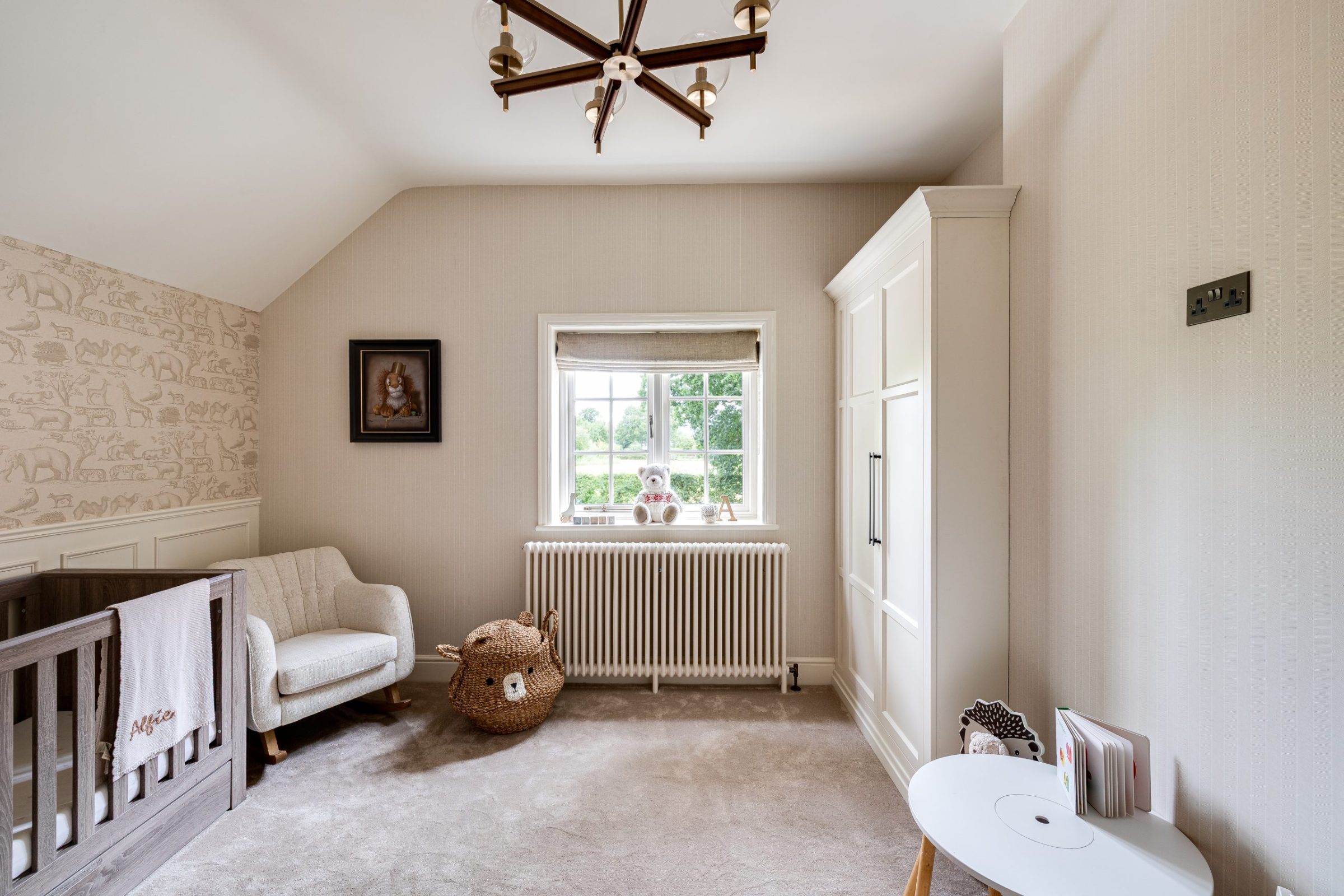 Nursery with neutral wallpaper, cream chair and natural textures