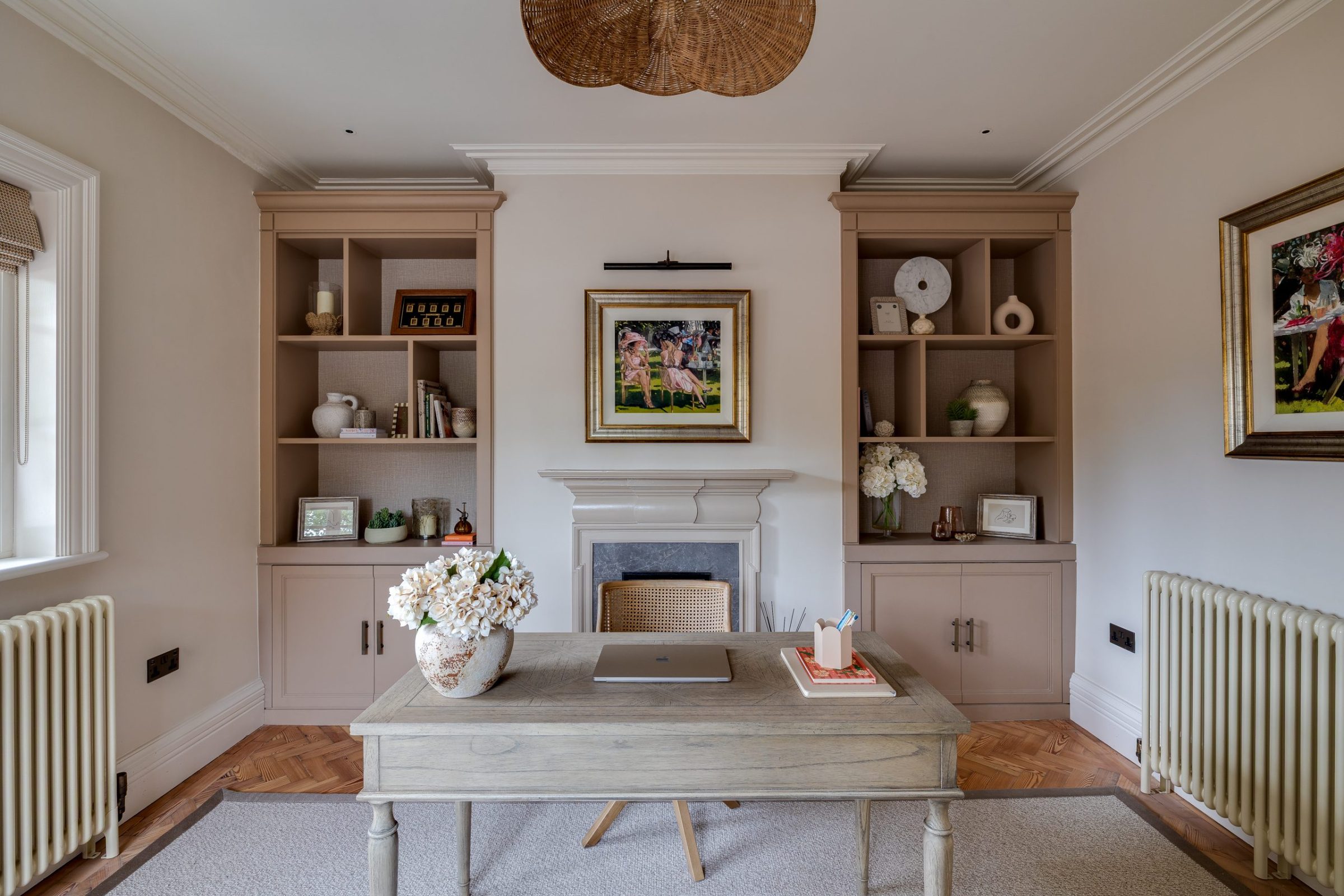 Home study with built-in shelving, central desk and soft blush-toned joinery