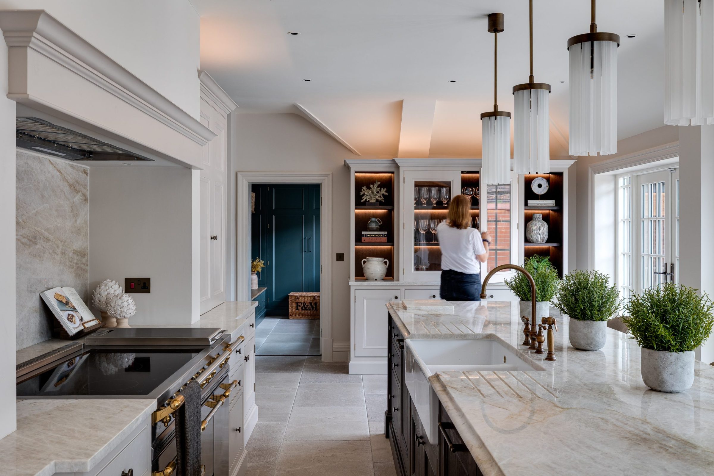 A bright kitchen with a marble island and Helen styling a cabinet.