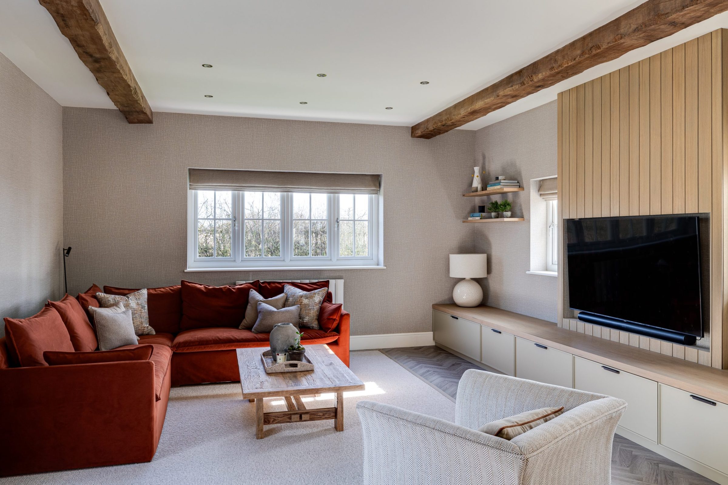 A cosy living room with a red sofa and built-in storage.