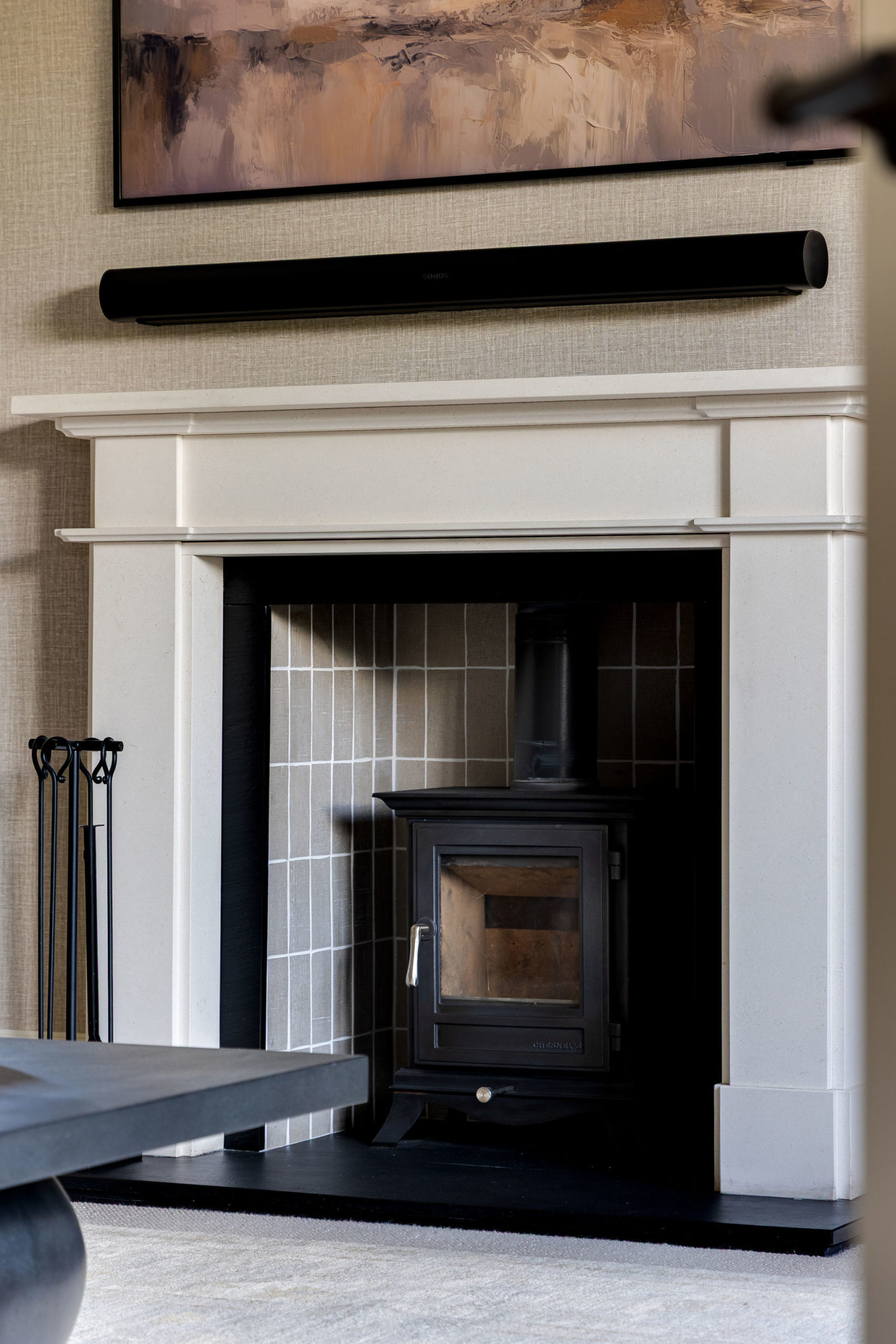 Close-up of contemporary fireplace with black wood stove and minimalist mantel design.