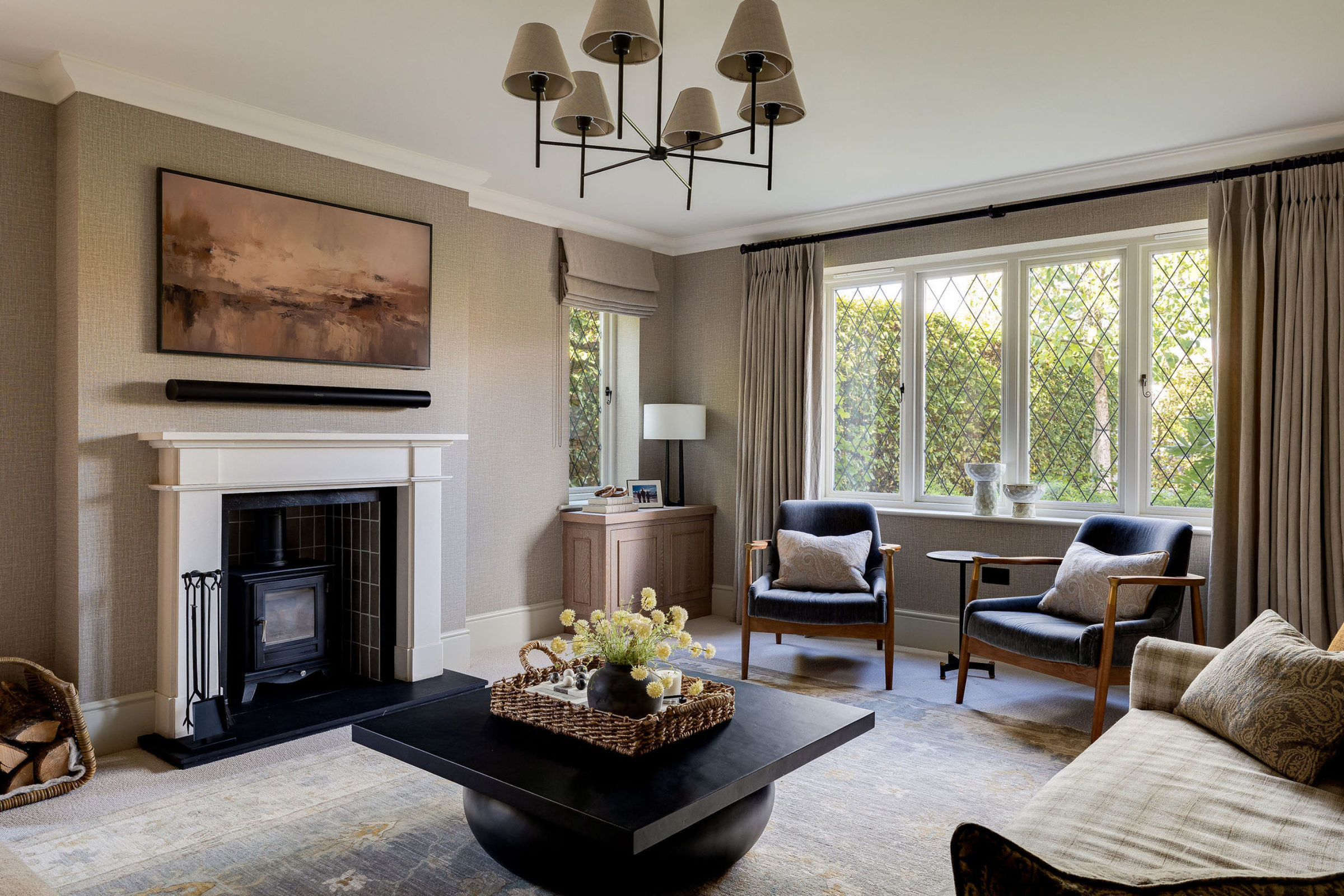 Sophisticated living room with modern fireplace, black coffee table, and large window with draped curtains.
